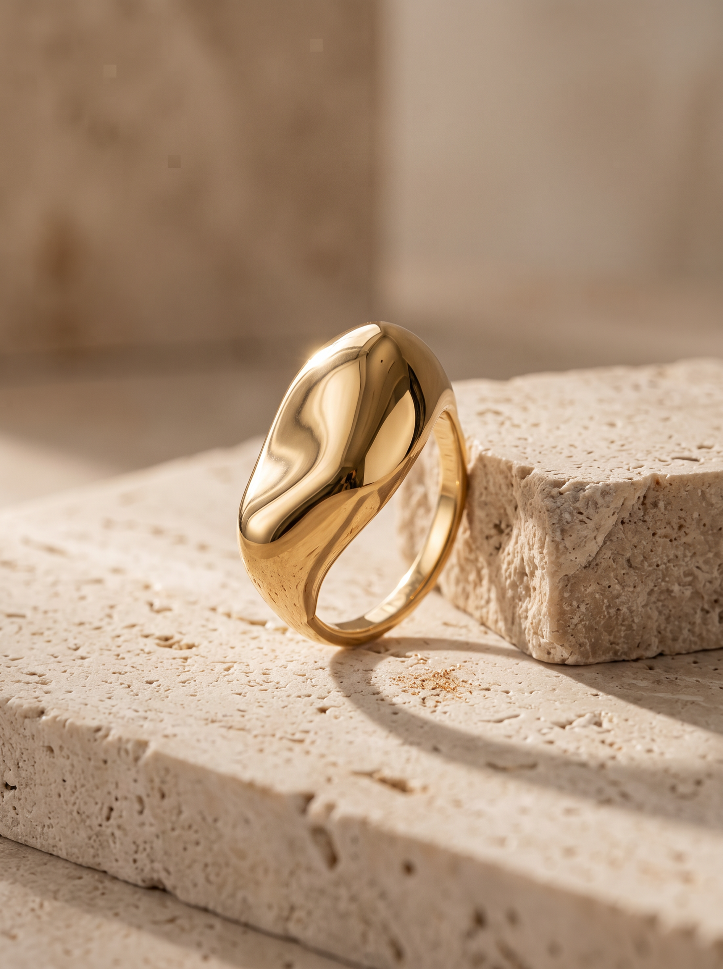 Bague galet dorée portée à l'annulaire, volume bombé poli miroir