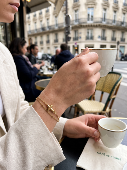 Bracelet chaîne fine à croix dorée porté au poignet
